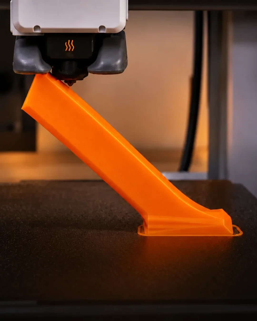 An orange printable finishing tool being made on a 3D printer